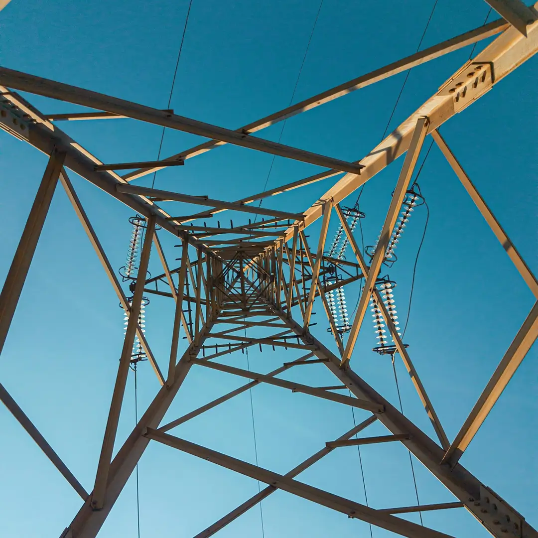 Strommast vor blauem Himmel, symbolisiert technische Präzision und zuverlässige Messungen im Bereich Engineering und Energienetze.