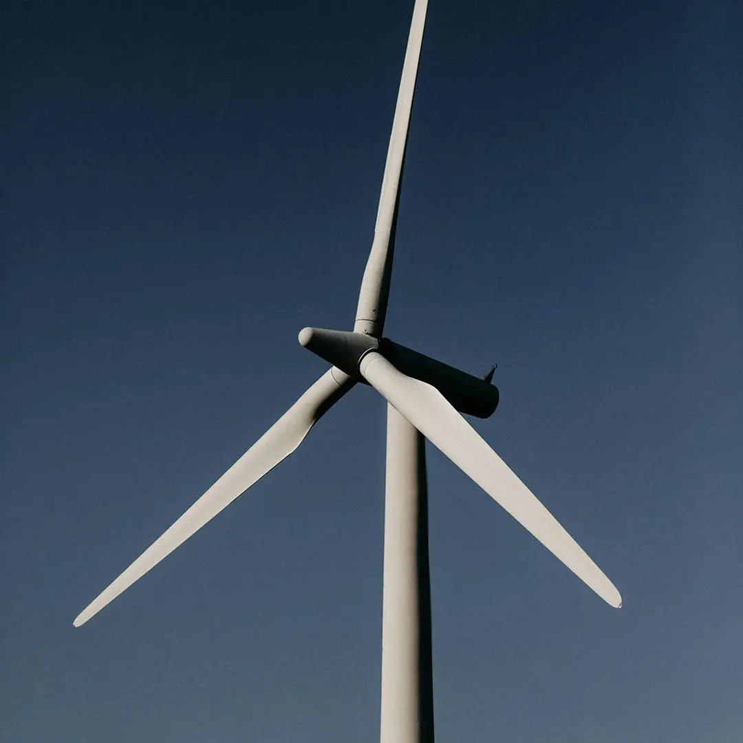 Oberer Teil eines Windrads, Rotorblätter vor einem klaren Himmel – Symbol für nachhaltige Energie und technologische Exzellenz.