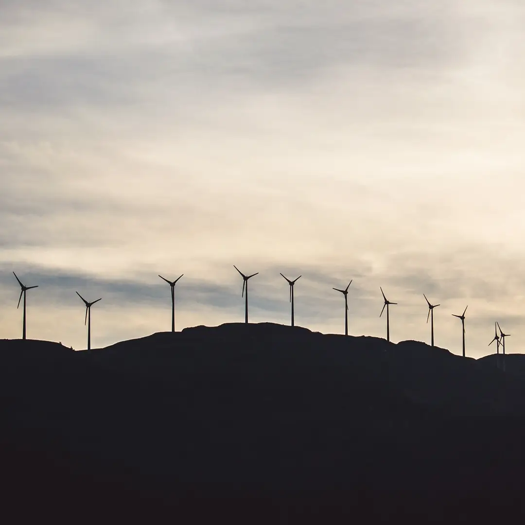 Windräder auf einem Gebirgskamm im Horizont, die nachhaltige Energiegewinnung und die Vision von AURORA nextGen power – eine nachhaltige Energiewende – symbolisieren.