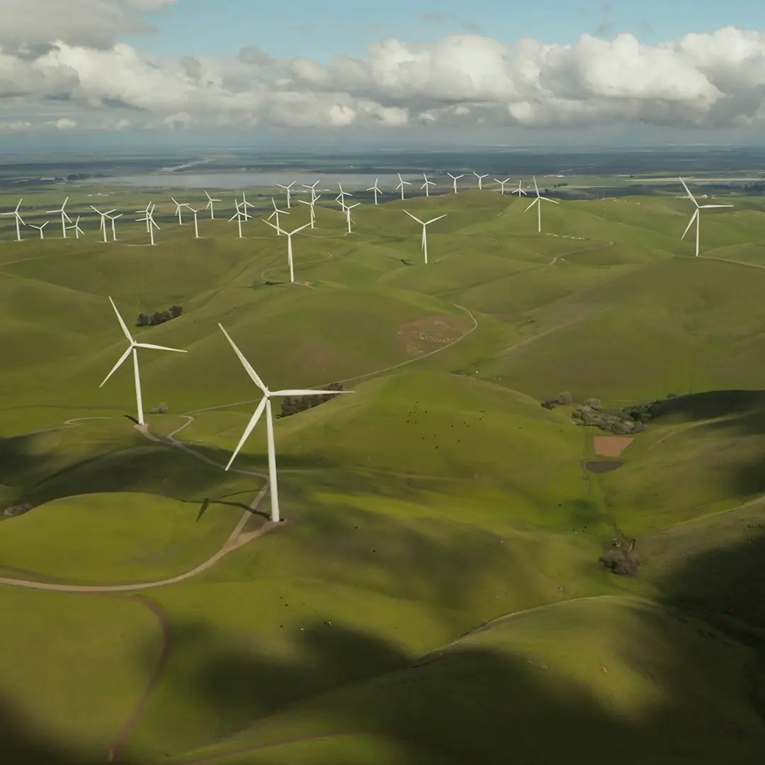 Luftaufnahme von Windrädern in einer grünen Landschaft – ein Symbol für nachhaltige Energiegewinnung und den Übergang zu erneuerbaren Energien.