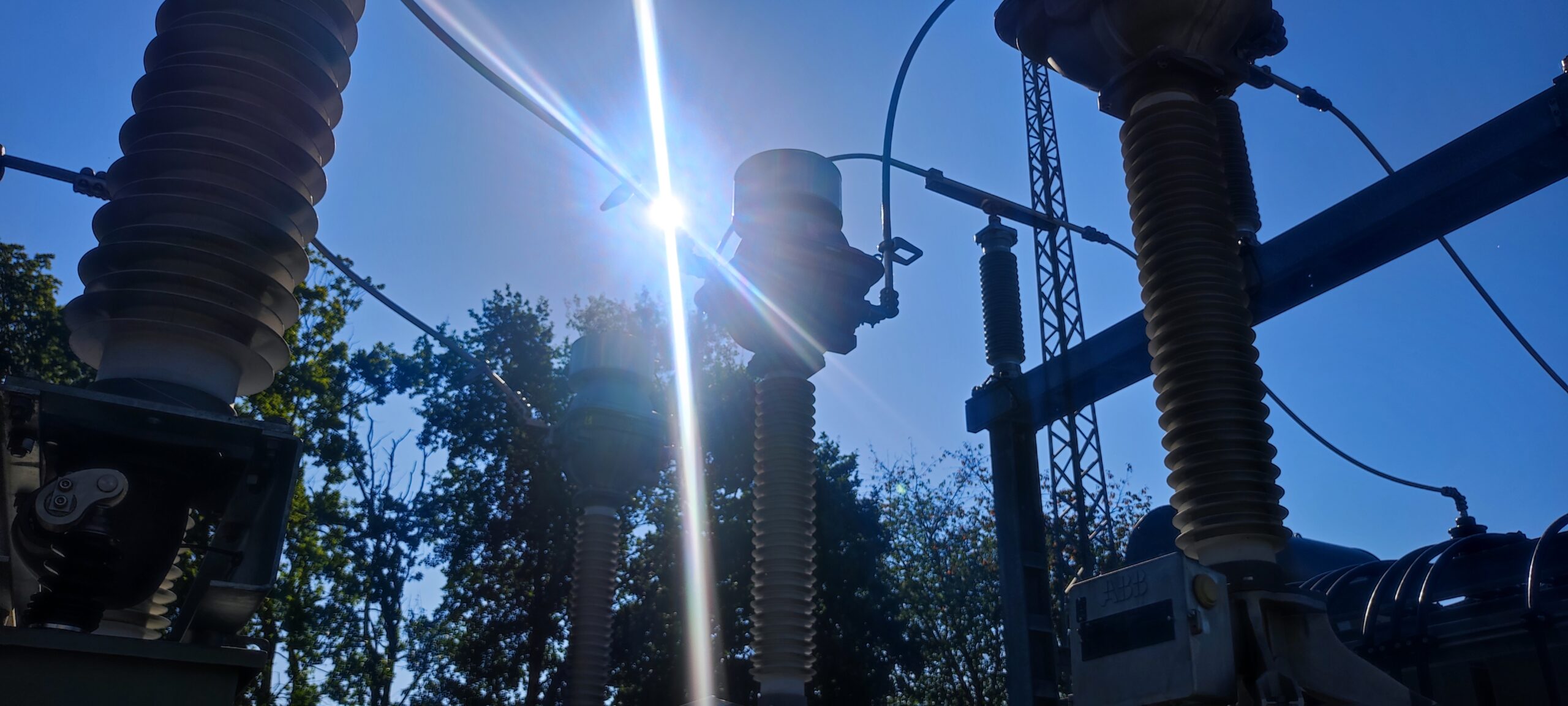 Hochspannungskomponenten eines Umspannwerks im Sonnenlicht